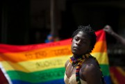 A transgender Ugandan poses in front of a rainbow flag during the third annual LGBT Pride celebrations in Entebbe, Uganda, Aug. 9, 2014 (AP photo by Rebecca Vassie).