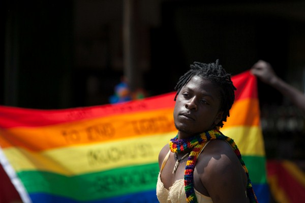 A transgender Ugandan poses in front of a rainbow flag during the third annual LGBT Pride celebrations in Entebbe, Uganda, Aug. 9, 2014 (AP photo by Rebecca Vassie).