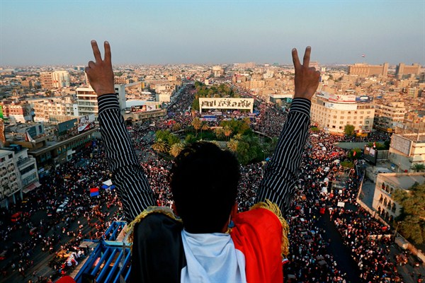 A protester flashes the victory sign overlooking a huge anti-government rally in Tahrir Square, Baghdad, Iraq, Oct. 31, 2019 (AP photo by Hadi Mizban).