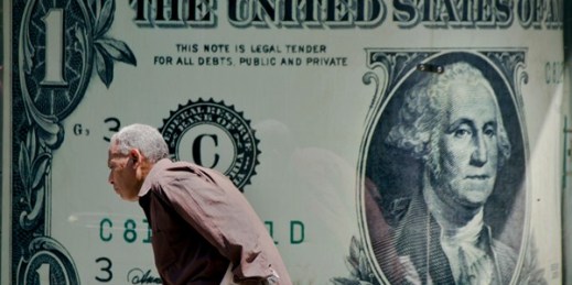 A man walks past a poster showing a U.S. dollar outside an exchange office in Cairo, Egypt, Aug. 17, 2016 (AP photo by Amr Nabil).