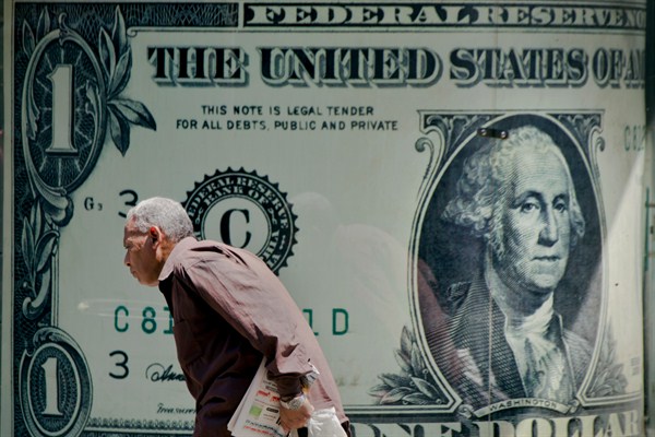 A man walks past a poster showing a U.S. dollar outside an exchange office in Cairo, Egypt, Aug. 17, 2016 (AP photo by Amr Nabil).