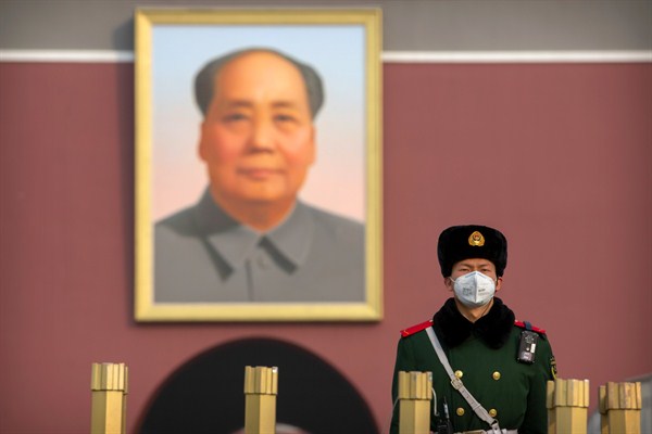 A paramilitary policeman wears a face mask as he stands guard near the large portrait of Chinese leader Mao Zedong at Tiananmen Gate in Beijing, Jan. 27, 2020 (AP photo by Mark Schiefelbein).