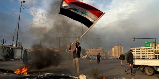 A protester waves the national flag near Tahrir Square during a demonstration against an Iranian missile strike, in Baghdad, Iraq, Jan. 8, 2020 (AP photo by Khalid Mohammed).