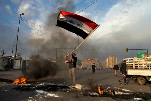 A protester waves the national flag near Tahrir Square during a demonstration against an Iranian missile strike, in Baghdad, Iraq, Jan. 8, 2020 (AP photo by Khalid Mohammed).