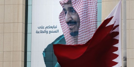 A Qatari flag flies in front of a banner showing King Salman of Saudi Arabia, in Riyadh, Dec. 9, 2019 (AP photo by Amr Nabil).
