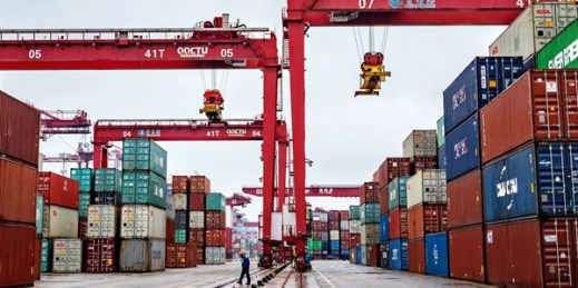 A worker walks past cranes at the container port in Qingdao, Shandong province, China, Jan. 14, 2020 (Chinatopix photo via AP Images).