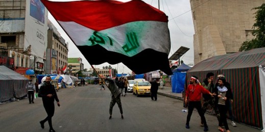 A man waves an Iraqi flag during anti-government demonstrations in Tahrir Square, Baghdad, Iraq, Feb. 9, 2020 (AP photo by Khalid Mohammed).