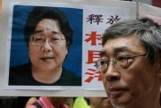 Freed Hong Kong bookseller Lam Wing-kee stands next to a placard with a picture of Gui Minhai, Hong Kong, June 18, 2016 (AP photo by Kin Cheung).