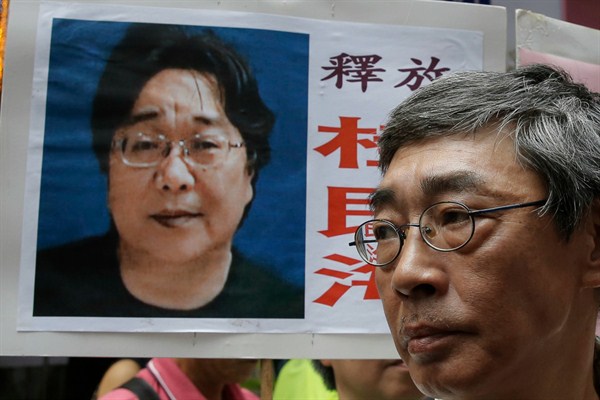 Freed Hong Kong bookseller Lam Wing-kee stands next to a placard with a picture of Gui Minhai, Hong Kong, June 18, 2016 (AP photo by Kin Cheung).