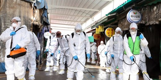 Workers wearing protective suits spray disinfectant at a market in Bupyeong, South Korea, Feb. 24, 2020 (Newsis photo by Lee Jong-chul via AP Images).