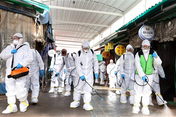 Workers wearing protective suits spray disinfectant at a market in Bupyeong, South Korea, Feb. 24, 2020 (Newsis photo by Lee Jong-chul via AP Images).