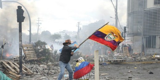 An anti-government demonstrator waves an Ecuadorian national flag during clashes with police in Quito, Ecuador, Oct. 12, 2019 (AP photo by Fernando Vergara).