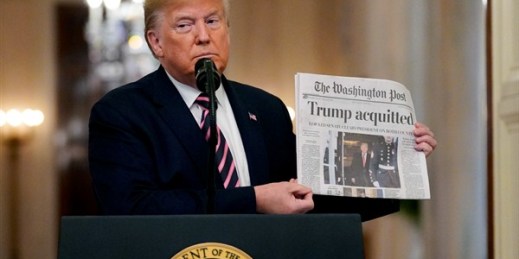President Donald Trump holds up a newspaper with a headline that reads “Trump acquitted” during an event in the East Room of the White House, Washington, Feb. 6, 2020 (AP photo by Evan Vucci).