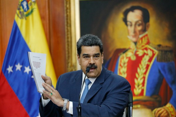 President Nicolas Maduro holds up a copy of his country’s case taken to the International Criminal Court regarding U.S. sanctions, Caracas, Venezuela, Feb. 14, 2020 (AP photo by Ariana Cubillos).