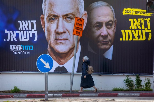 A woman walks by an election campaign billboard for the opposition Blue and White party in Ramat Gan, Israel, Feb. 20, 2020 (AP photo by Oded Balilty).