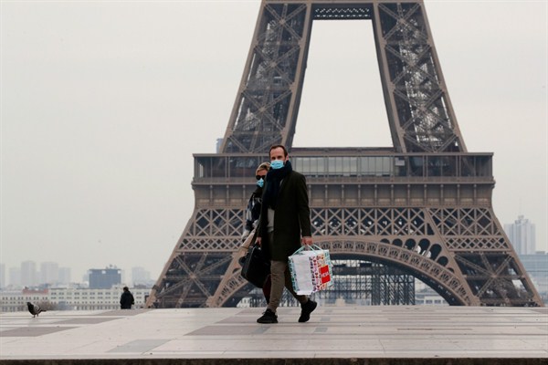 A masked couple walks on the empty Trocadero next to the Eiffel Tower, in Paris, March 17, 2020 (AP photo by Francois Mori).