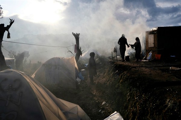 Migrants stand outside their makeshift tents on the perimeter of the overcrowded Moria refugee camp on Lesbos, Greece, Jan. 28, 2020 (AP photo by Aggelos Barai).