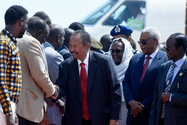 Sudan’s prime minister, Abdallah Hamdok, center, is welcomed upon his arrival in Juba, South Sudan, Sept. 12, 2019 (AP photo by Charles Atiki Lomodong).