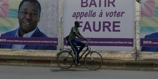 A man rides a bicycle past election posters of Togo’s president, Faure Gnassingbe, on the street in Lome, Togo, Feb. 21, 2020 (AP photo by Sunday Alamba).