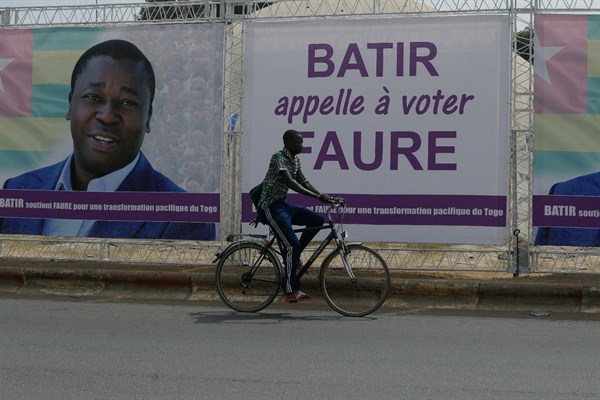 A man rides a bicycle past election posters of Togo’s president, Faure Gnassingbe, on the street in Lome, Togo, Feb. 21, 2020 (AP photo by Sunday Alamba).