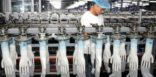 A man works on a production line in a factory that produces medical gloves, in Suixi, China, Aug. 14, 2019 (Chinatopix photo via AP Images).