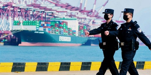 Police officers wearing face masks patrol at a container port in Qingdao, China, Feb. 19, 2020 (Chinatopix photo via AP Images).