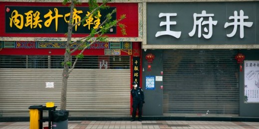 A security guard stands next to shuttered shops in Beijing, China, April 15, 2020 (AP photo by Mark Schiefelbein).