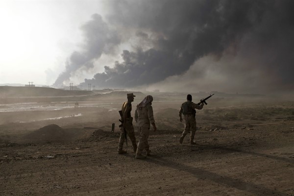 Iraqi soldiers man a checkpoint as oil wells burn on the outskirts of Qayyarah, Iraq, Oct. 19, 2016 (AP photo by Marko Drobnjakovic).