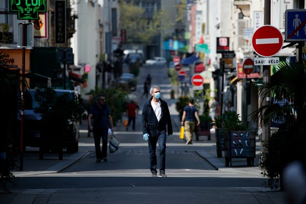 A man wearing a protective mask walks in the middle of the street in Paris, April 10, 2020 (AP photo by Francois Mori).
