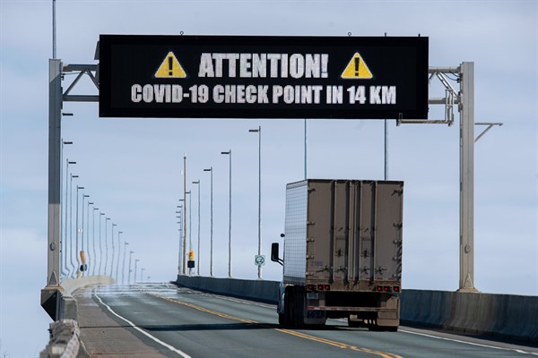 A sign indicates a COVID-19 checkpoint ahead as a truck crosses the Confederation Bridge in Cape Jourimain, New Brunswick, Canada, March 22, 2020 (photo by Andrew Vaughan for The Canadian Press via AP).