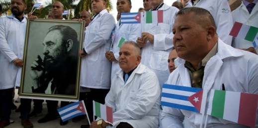 Cuban doctors and medical professionals pose with a photo of Fidel Castro before departing for Italy to assist with the coronavirus outbreak in the country, Havana, Cuba, March 21, 2020 (AP photo by Ismael Francisco).