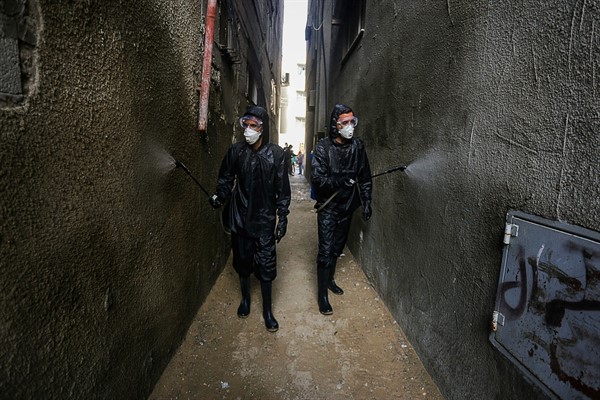 Palestinian health workers spray disinfectant in a residential area to try and limit the spread of the coronavirus, in Khan Yunis, Gaza Strip, April 9, 2020 (Photo by Yousef Masoud for Sipa via AP Images).