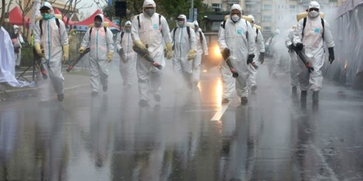 Taiwanese army soldiers wearing protective suits spray disinfectant over a road in New Taipei City, Taiwan, March 14, 2020 (AP photo by Chiang Ying-ying).