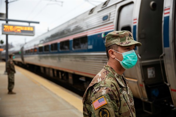Members of the Rhode Island National Guard look for passengers getting off a train from New York, in Westerly, Rhode Island, March 28, 2020 (AP photo by David Goldman).