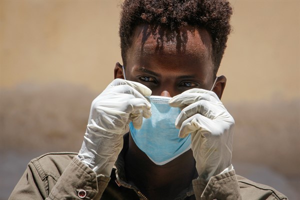 A man wearing a surgical mask and gloves in Mogadishu, Somalia, March 18, 2020 (AP photo by Farah Abdi Warsameh).