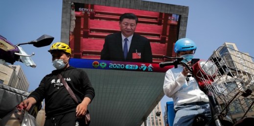 Food delivery workers near a TV screen showing Chinese leader Xi Jinping attending the closing ceremony of the National People’s Congress, in Beijing, China, May 28, 2020 (AP photo by Andy Wong).
