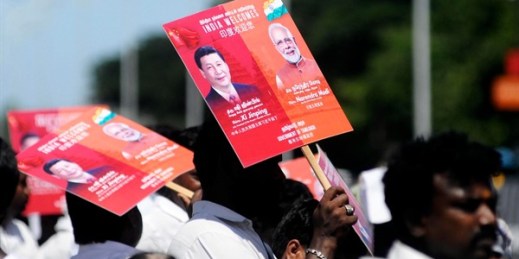 People hold placards with portraits of Chinese leader Xi Jinping and Indian Prime Minister Narendra Modi, as they wait to welcome Xi outside the airport in Chennai, India, Oct. 11, 2019 (AP photo by R. Parthibhan).