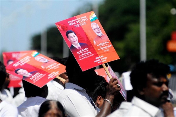 People hold placards with portraits of Chinese leader Xi Jinping and Indian Prime Minister Narendra Modi, as they wait to welcome Xi outside the airport in Chennai, India, Oct. 11, 2019 (AP photo by R. Parthibhan).
