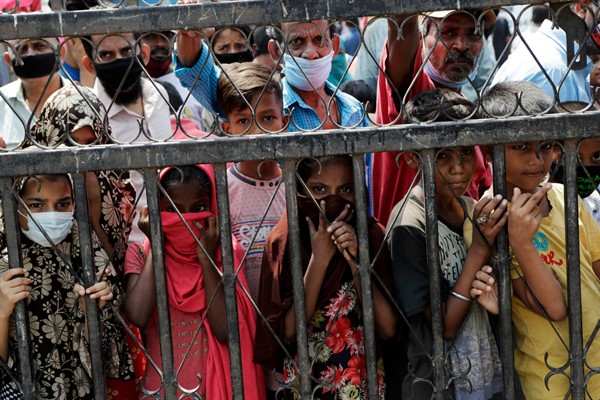 Children wait to receive free food distributed in a slum in Mumbai, India, April 18, 2020 (AP photo by Rajanish Kakade).