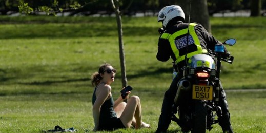 A woman is told to go home by a police officer on a motorbike to stop the spread of the coronavirus, on Primrose Hill, London, April 5, 2020 (AP photo by Matt Dunham).
