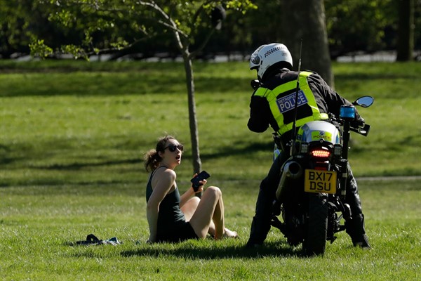 A woman is told to go home by a police officer on a motorbike to stop the spread of the coronavirus, on Primrose Hill, London, April 5, 2020 (AP photo by Matt Dunham).