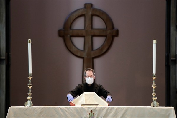 Sacristan Michael Seewar prepares the altar for a livestream Easter service at Saint Mark’s Episcopal Cathedral in Seattle, Washington, April 12, 2020 (AP photo by Elaine Thompson).