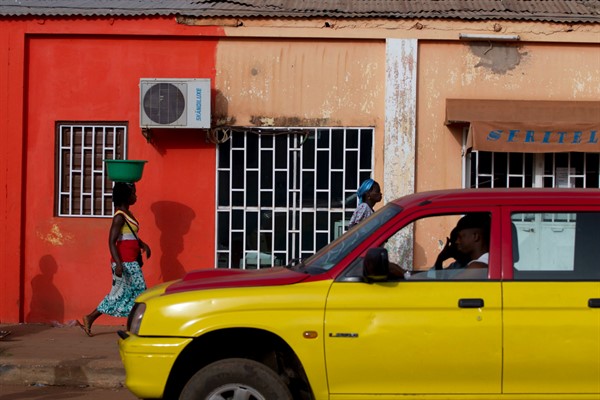 A car passes as women return from a fishing port in central Bissau, Guinea-Bissau, May 27, 2012 (AP photo by Rebecca Blackwell).