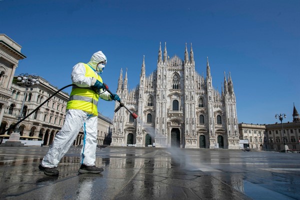 A worker sprays disinfectant to sanitize Duomo square in Milan, Italy, March 31, 2020 (AP photo by Luca Bruno).