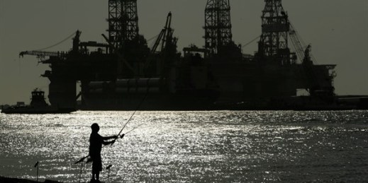 A man fishes near docked oil drilling platforms, in Port Aransas, Texas, May 8, 2020 (AP photo by Eric Gay).