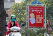 A motorcyclist drives past a poster calling on people to take care of their health amid the coronavirus pandemic, in Hanoi, Vietnam, April 14, 2020 (AP photo by Hau Dinh).