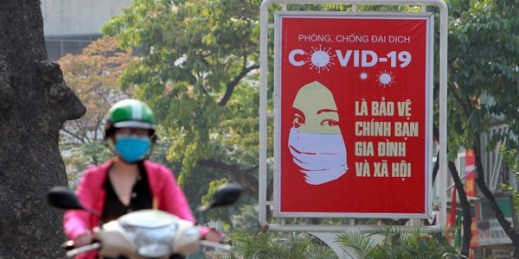 A motorcyclist drives past a poster calling on people to take care of their health amid the coronavirus pandemic, in Hanoi, Vietnam, April 14, 2020 (AP photo by Hau Dinh).