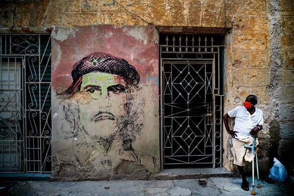 A man rests in the shade against a wall covered with a mural of Ernesto “Che” Guevara, in Havana, Cuba, June 8, 2020 (AP photo by Ramon Espinosa).