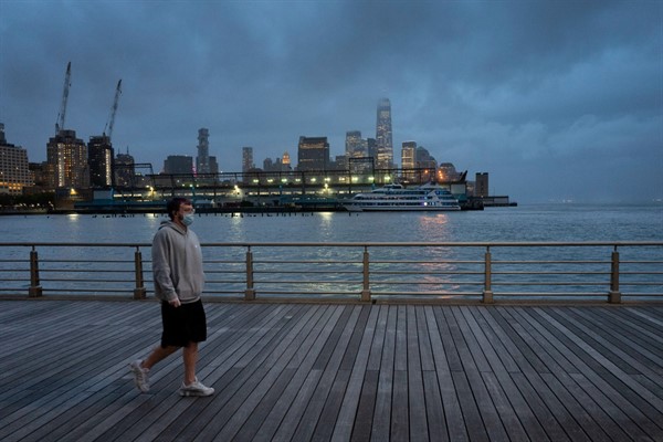A man wears a face mask as he walks on Pier 45 in New York, April 30, 2020 (AP photo by Mark Lennihan).