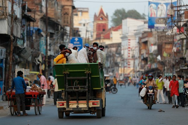 People wearing masks ride a mini truck in Prayagraj, India, May 23, 2020 (AP photo by Rajesh Kumar Singh).